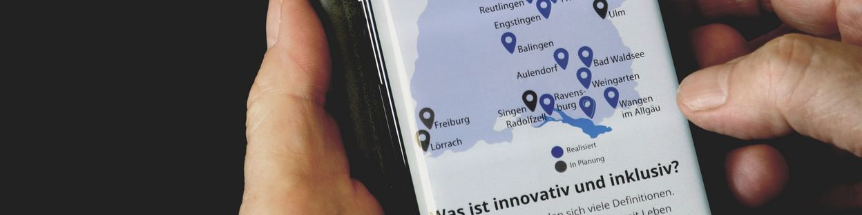 Eine Person hält ein Smartphone in der Hand. Darauf zu sehen ist die Online-Broschüre Innovation und Inklusion