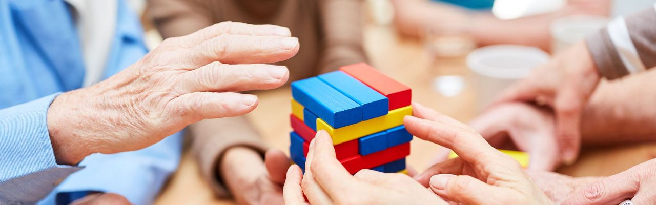 Hände, die Turm aus bunten Bausteinen bauen