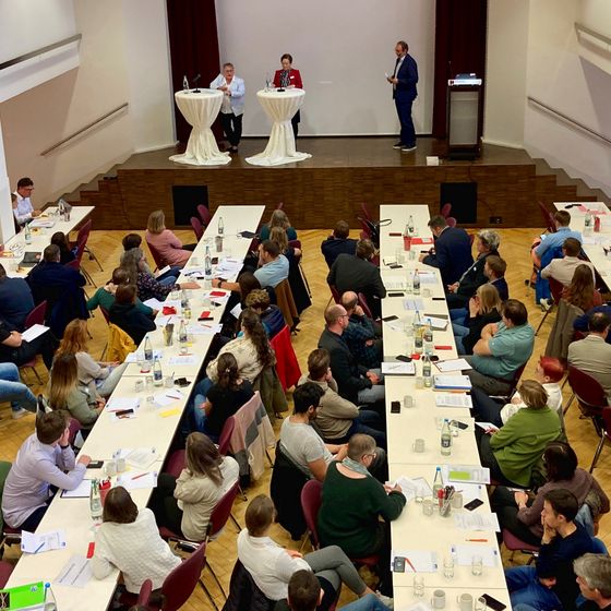 Das Publikum im großen Saal des Kolpinghauses blickt zu den Referentinnen auf der Bühne.